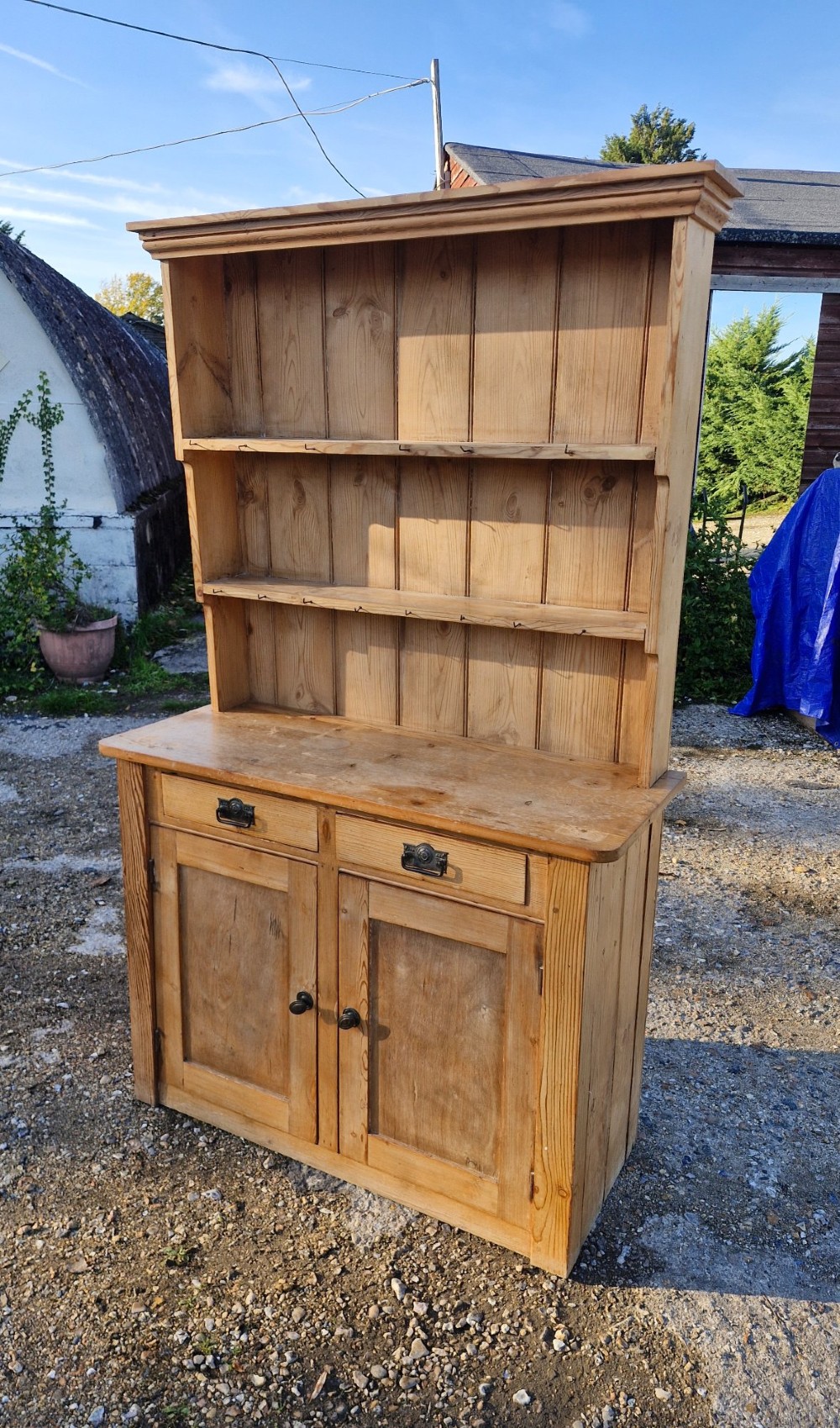 An early 20th-century natural pine kitchen dresser featuring a three-tier open shelf rack over two drawers and a two-door cabinet base. View IV