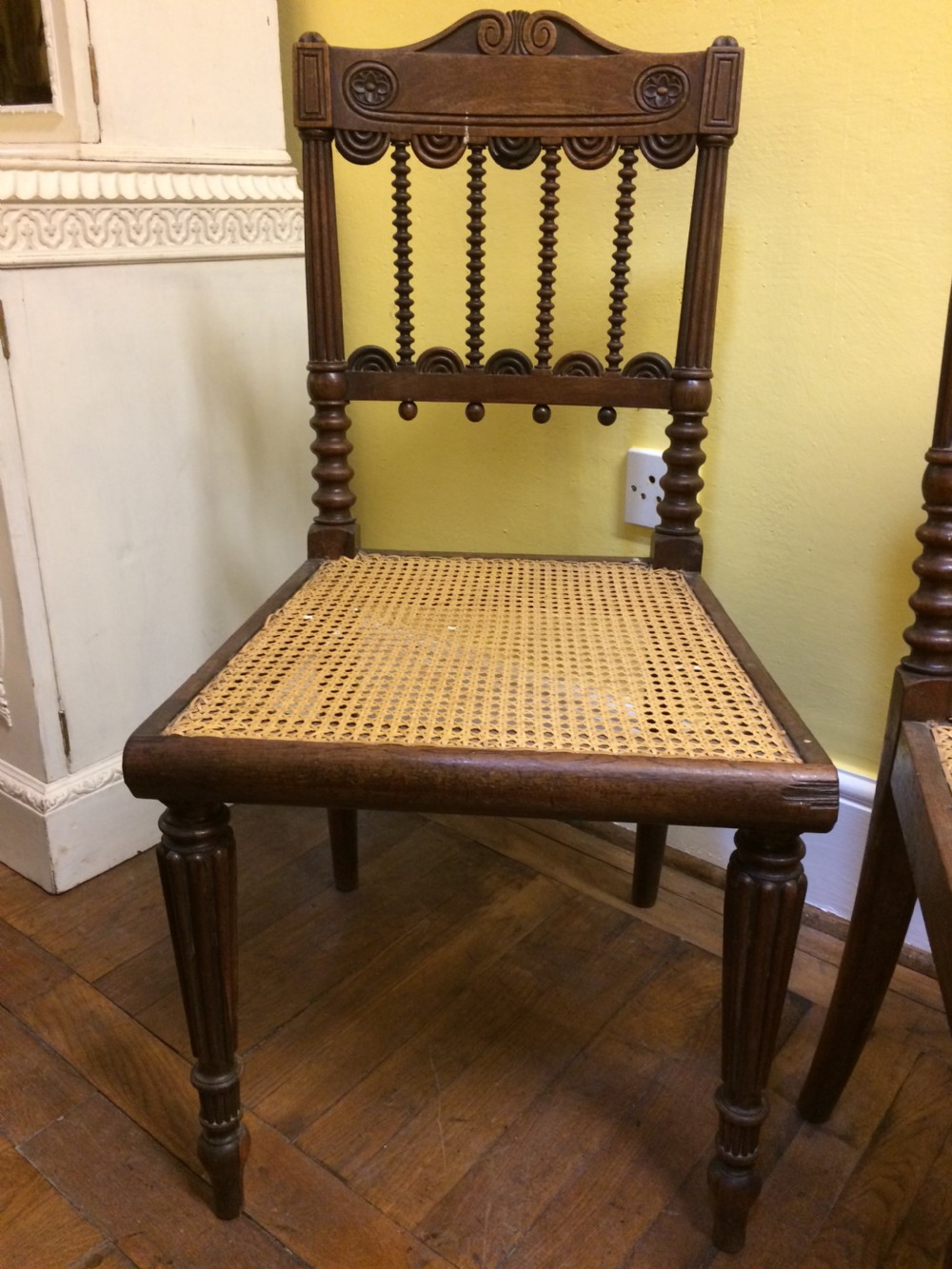 A pair of 19th-century carved dark rosewood side chairs featuring woven cane seats, spindle backrests, and fluted front legs. View II