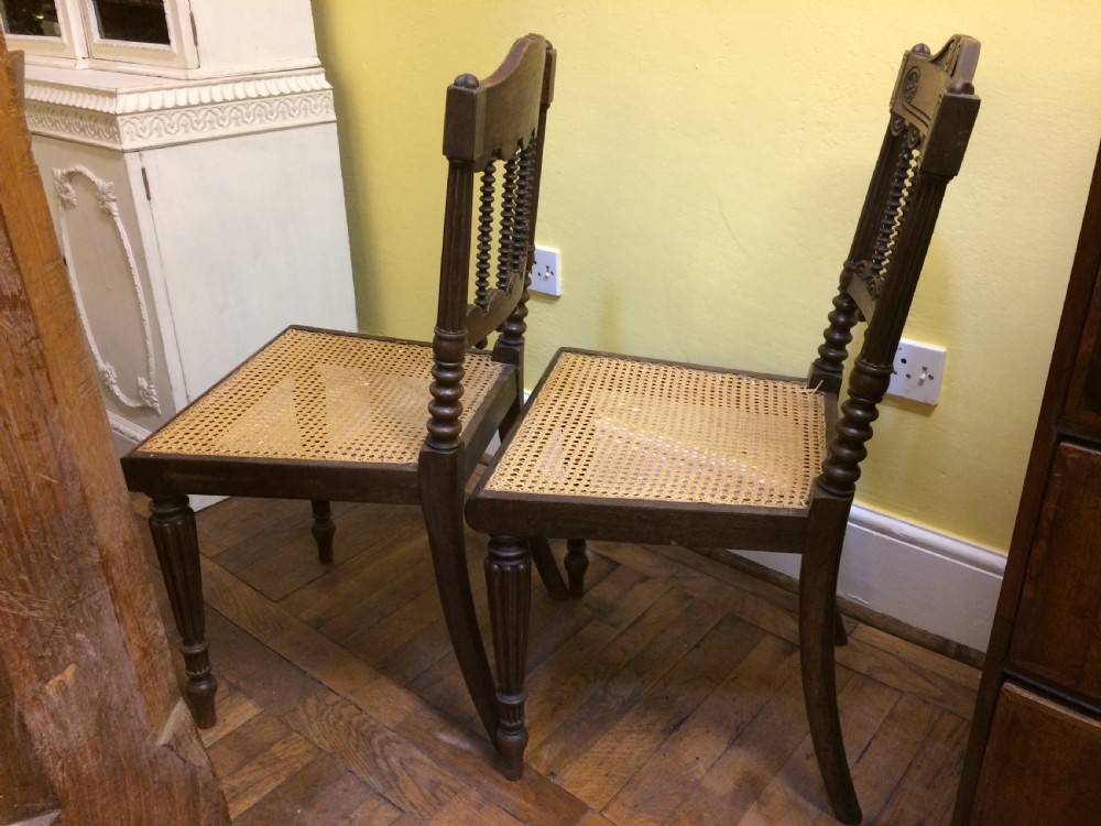 A pair of 19th-century carved dark rosewood side chairs featuring woven cane seats, spindle backrests, and fluted front legs. View III