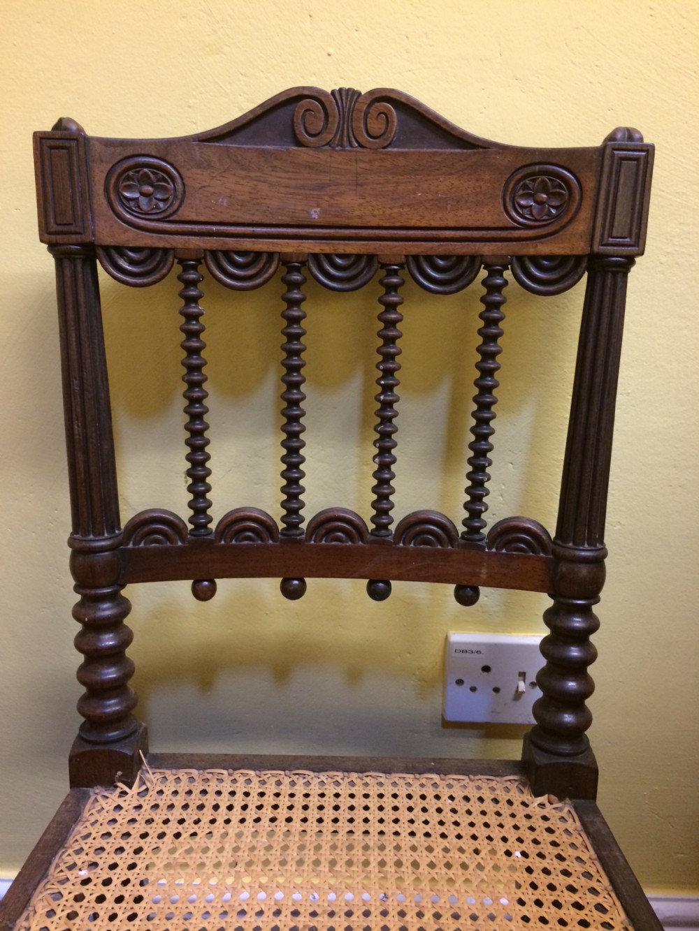 A pair of 19th-century carved dark rosewood side chairs featuring woven cane seats, spindle backrests, and fluted front legs. View VI
