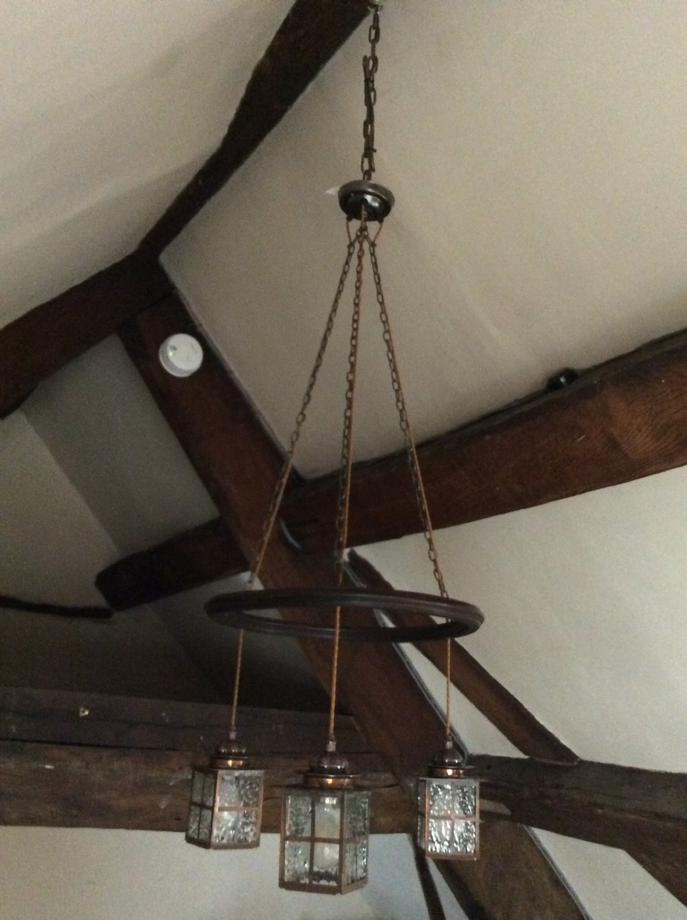 An Arts and Crafts style three-lantern ceiling light featuring a central circular dark frame suspended by chains with three hanging illuminated glass lanterns. View II