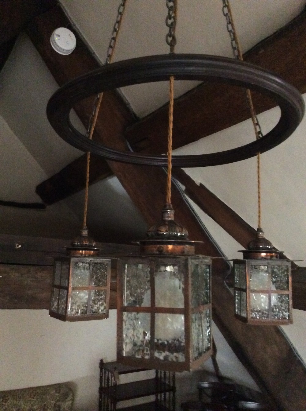 An Arts and Crafts style three-lantern ceiling light featuring a central circular dark frame suspended by chains with three hanging illuminated glass lanterns. View III