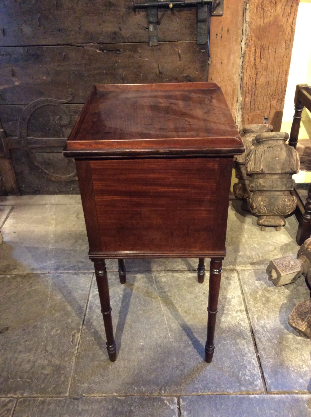 A Regency mahogany bedside cabinet featuring a gallery top, single flame mahogany door panel, and slender turned legs. View IV
