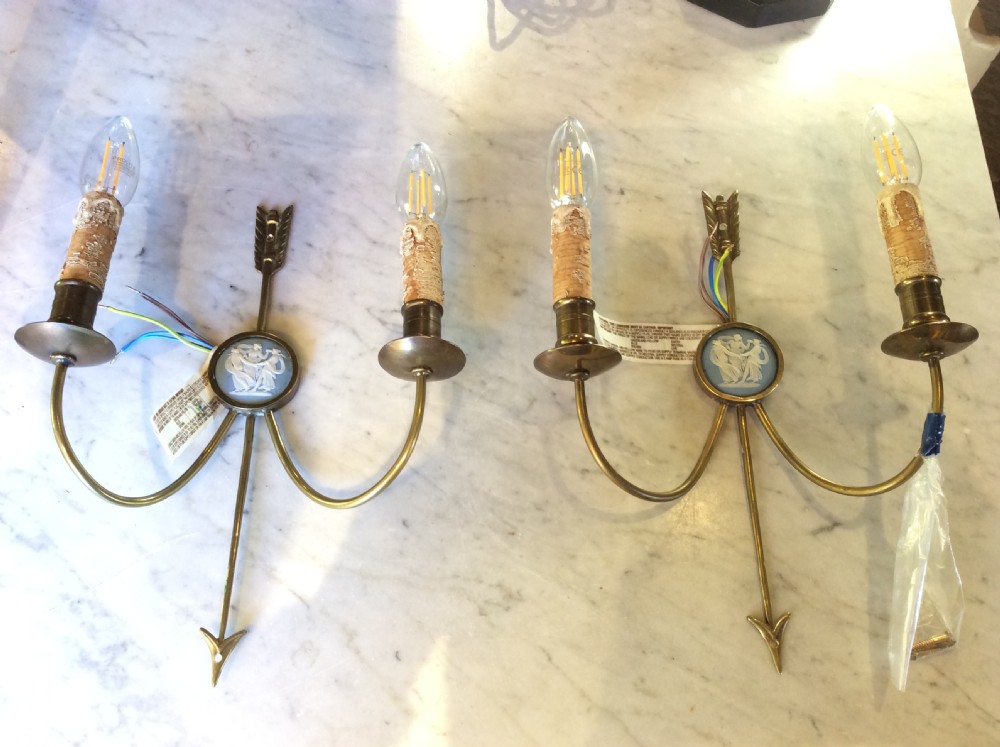 A pair of Edwardian brass twin-arm wall sconces featuring arrow motifs and circular blue jasperware medallions displaying white classical figures.
