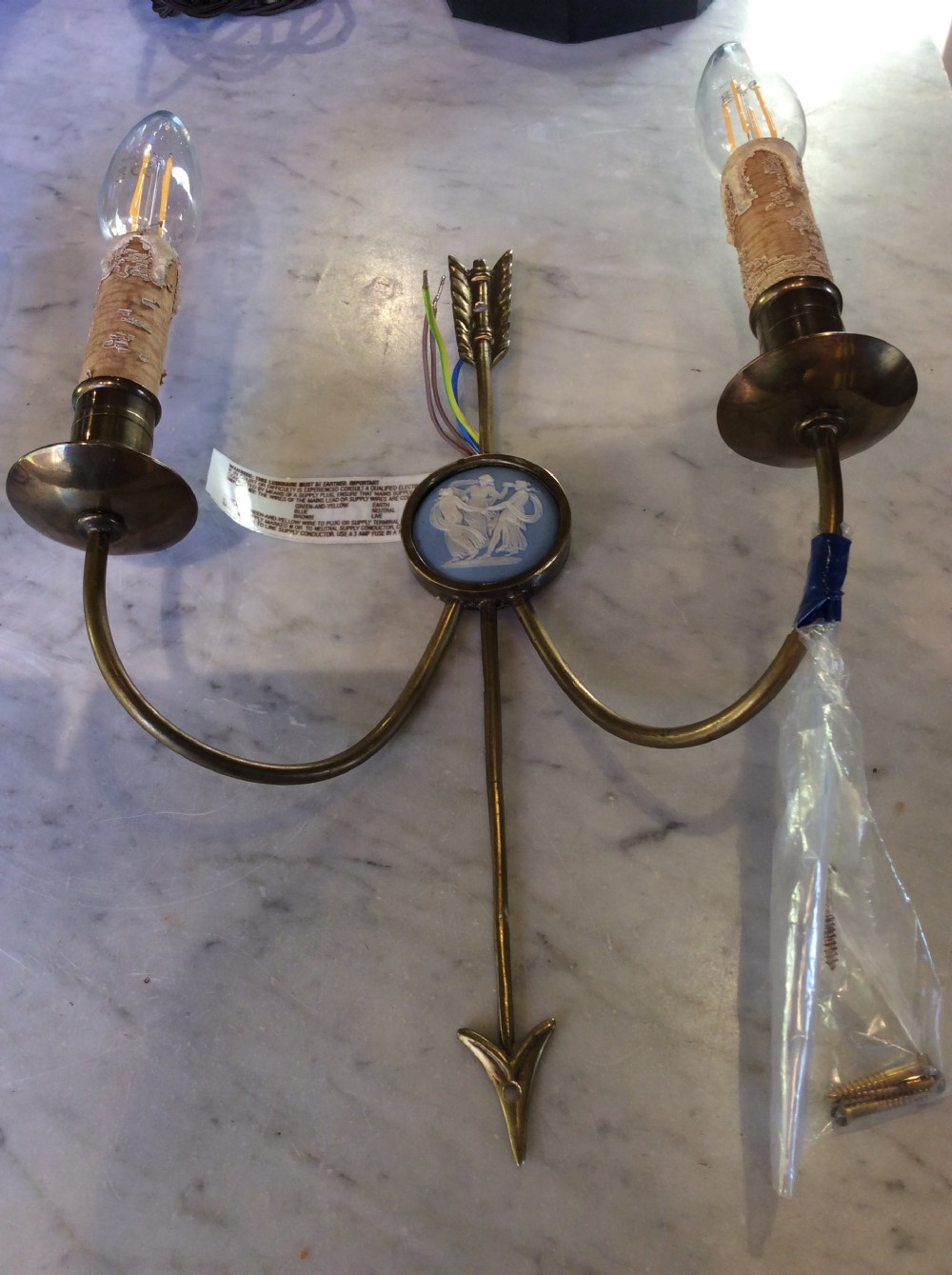 A pair of Edwardian brass twin-arm wall sconces featuring arrow motifs and circular blue jasperware medallions displaying white classical figures. View II