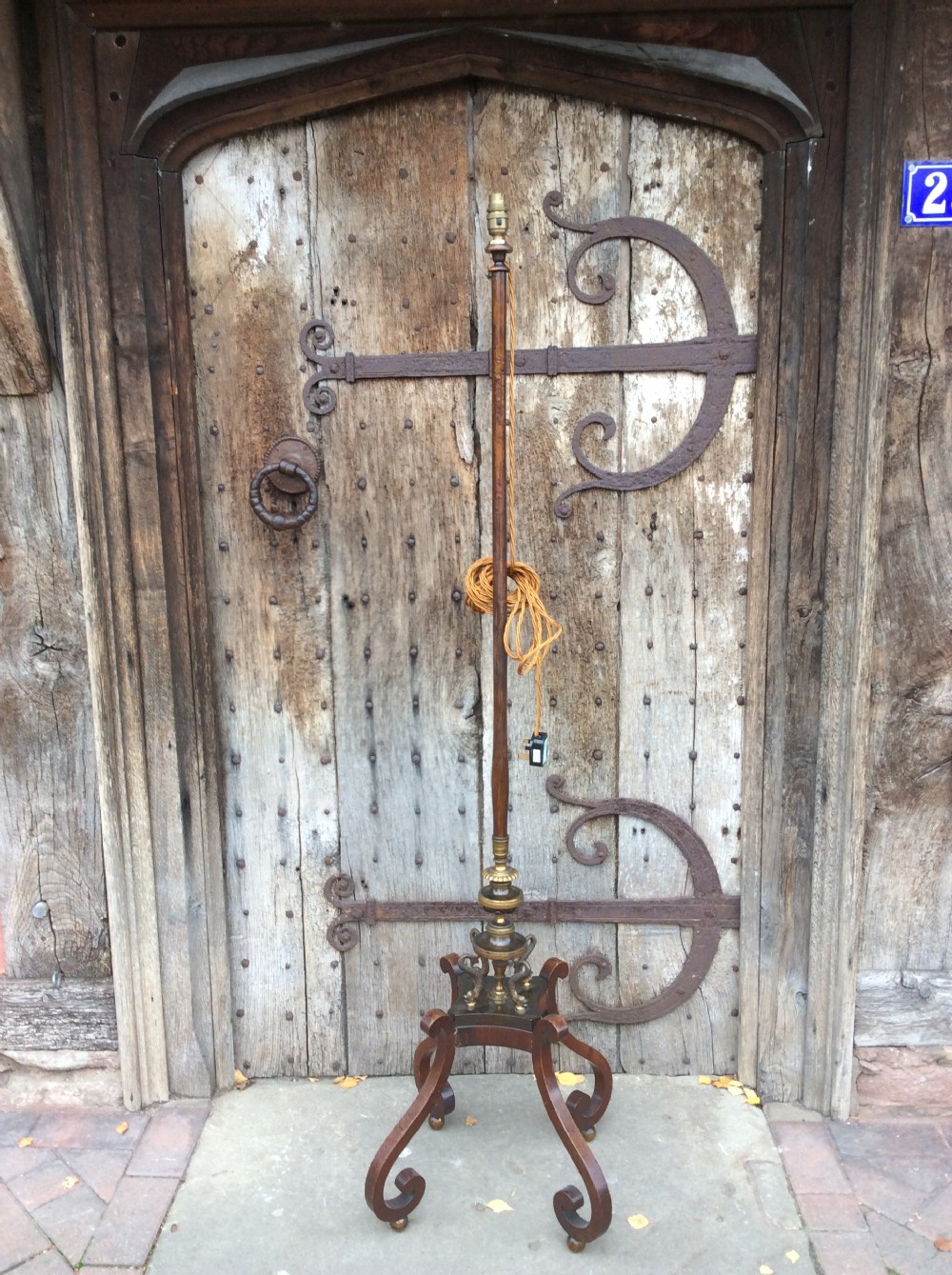 A 19th-century mahogany pole screen converted into a floor lamp featuring a slender turned shaft, gilt brass collars, and a scrolled tripod base. View VI