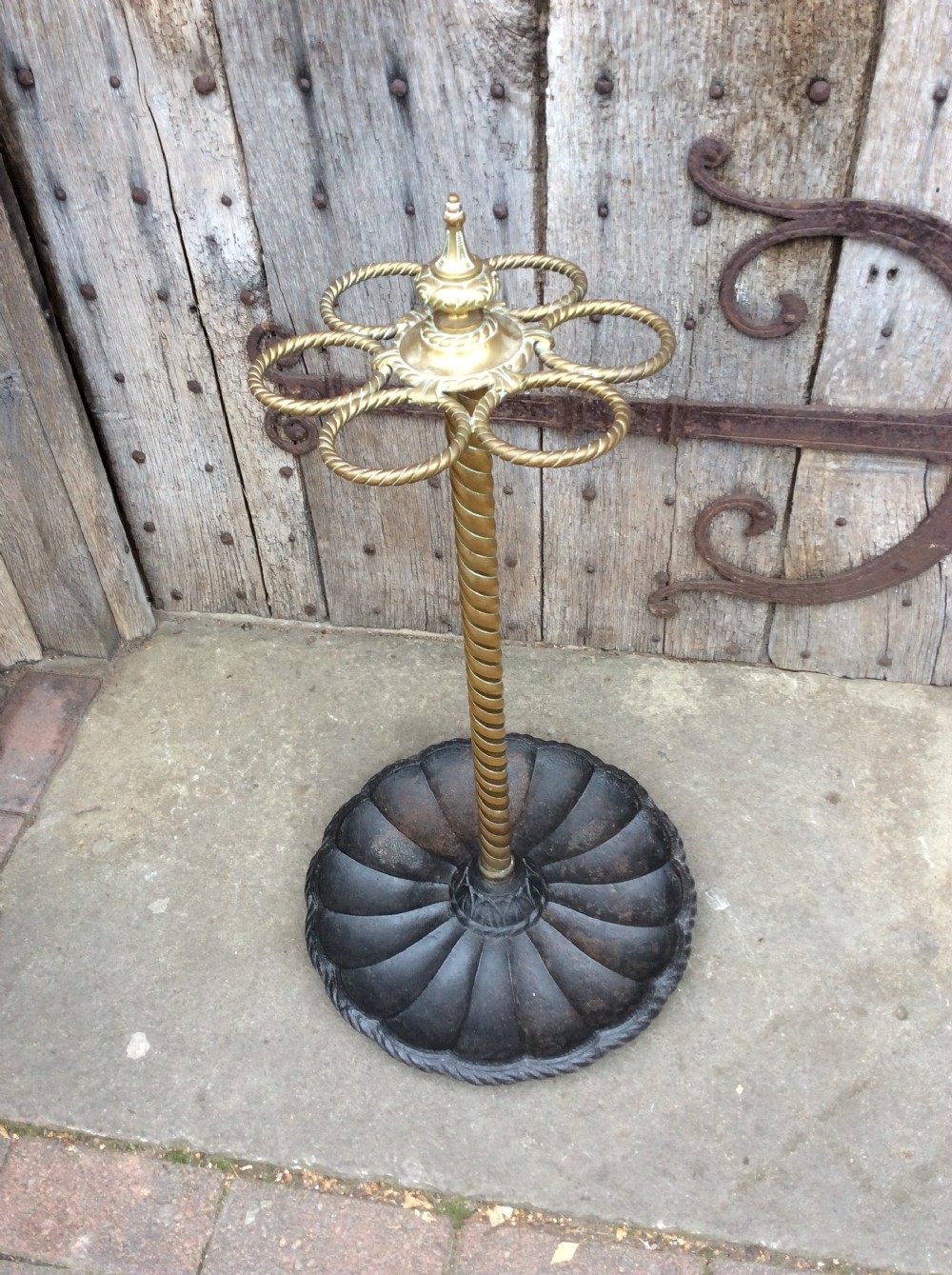 A Victorian brass and cast iron umbrella stand featuring a barley twist column, six circular divisions, and a scalloped drip tray base.