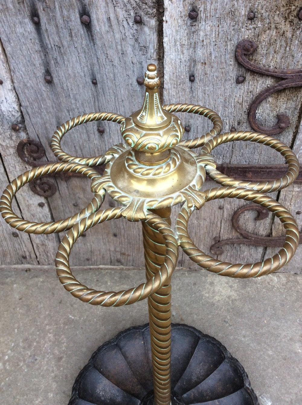 A Victorian brass and cast iron umbrella stand featuring a barley twist column, six circular divisions, and a scalloped drip tray base. View II