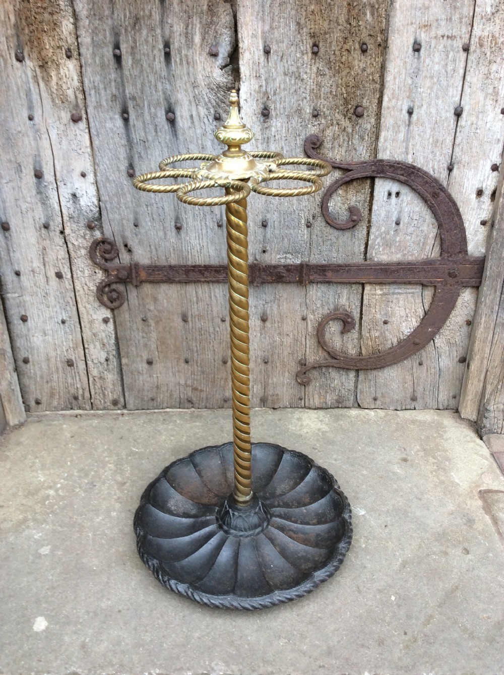 A Victorian brass and cast iron umbrella stand featuring a barley twist column, six circular divisions, and a scalloped drip tray base. View III