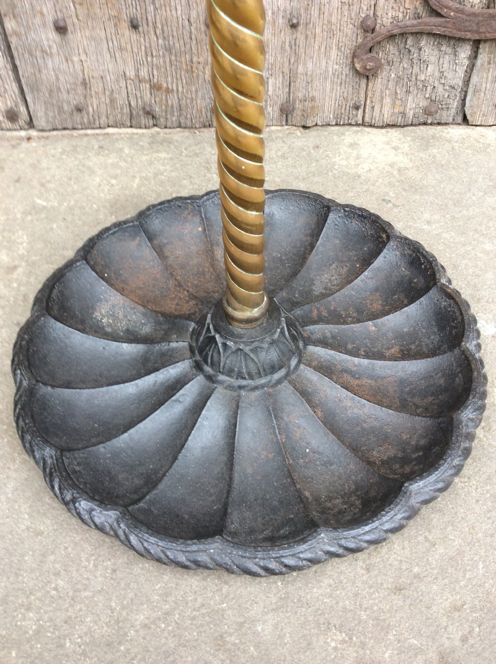 A Victorian brass and cast iron umbrella stand featuring a barley twist column, six circular divisions, and a scalloped drip tray base. View V