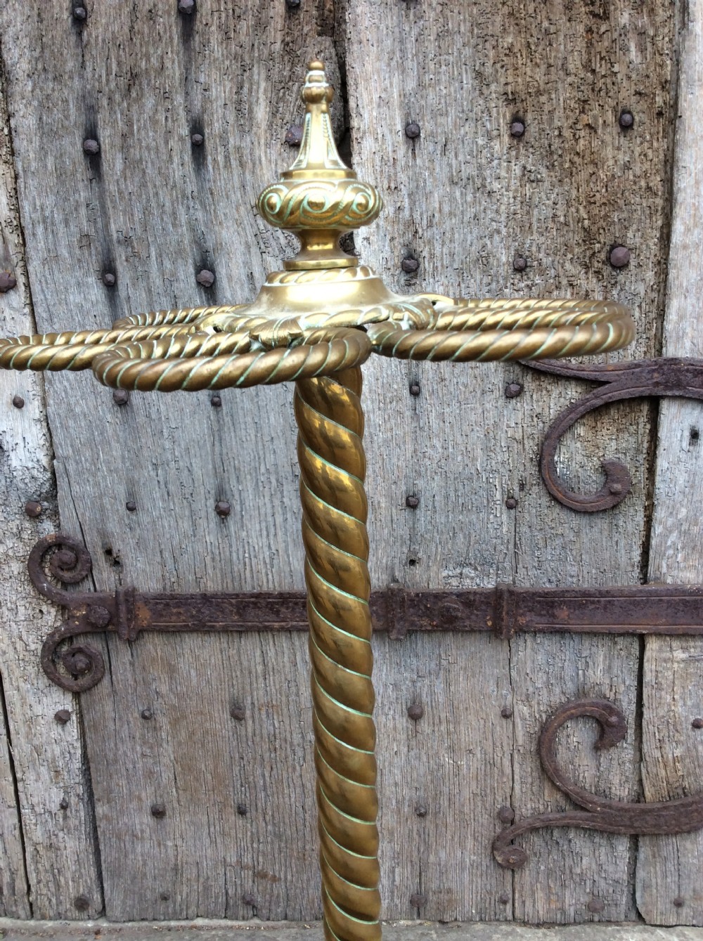 A Victorian brass and cast iron umbrella stand featuring a barley twist column, six circular divisions, and a scalloped drip tray base. View VI