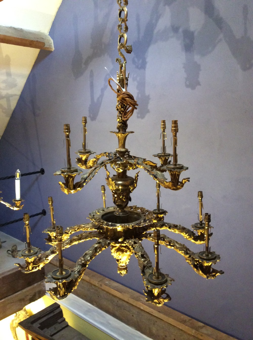 A two-tier gilt brass chandelier featuring twelve scrolling acanthus leaf branches holding electric candle fittings. View III