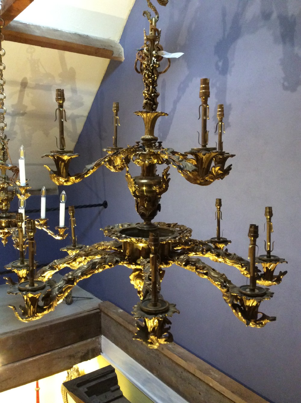 A two-tier gilt brass chandelier featuring twelve scrolling acanthus leaf branches holding electric candle fittings. View IV