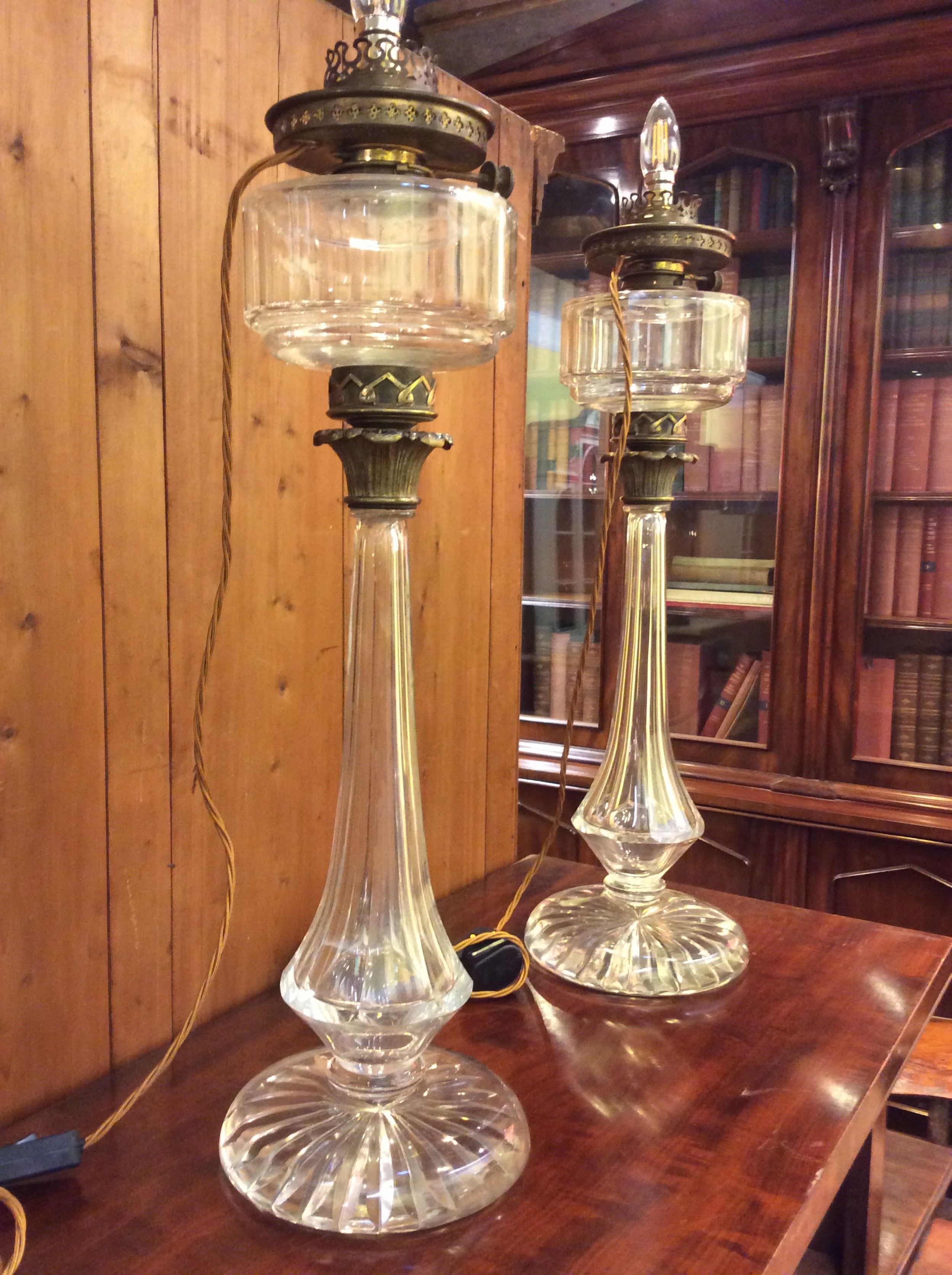 A pair of tall 19th-century clear cut glass table lamps featuring fluted column stems and brass gallery fittings.