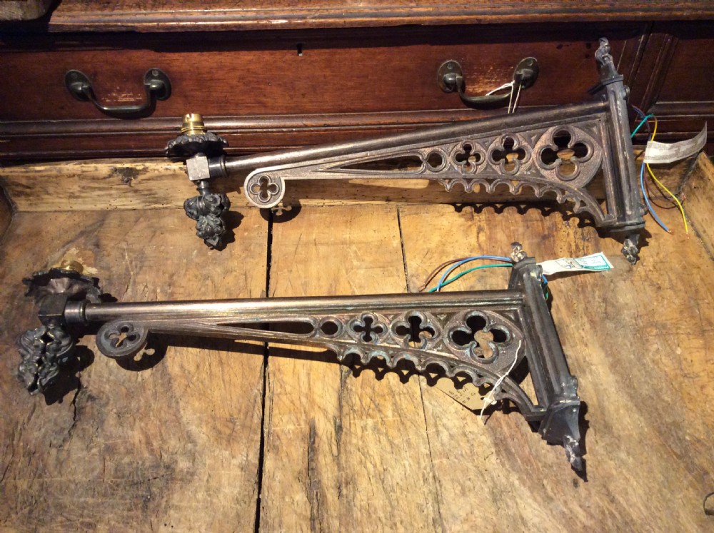 A pair of patinated dark brass Victorian Gothic wall light brackets featuring openwork tracery with trefoil motifs and detailed cast collars.