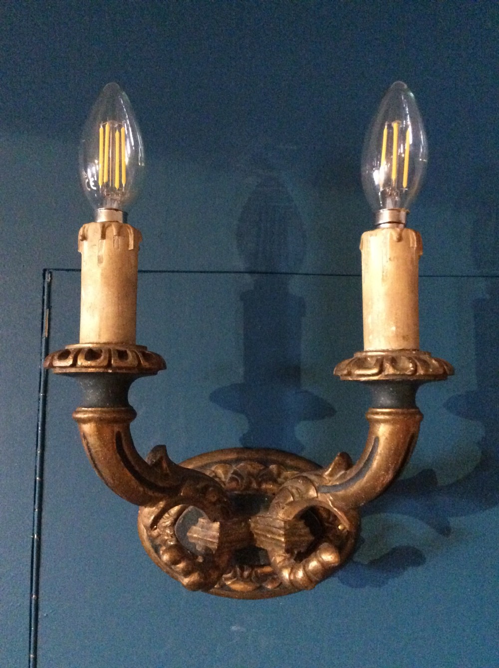 A pair of 19th-century carved and gilded twin-arm wall light brackets featuring faux candle sleeves and decorative scrollwork. View II