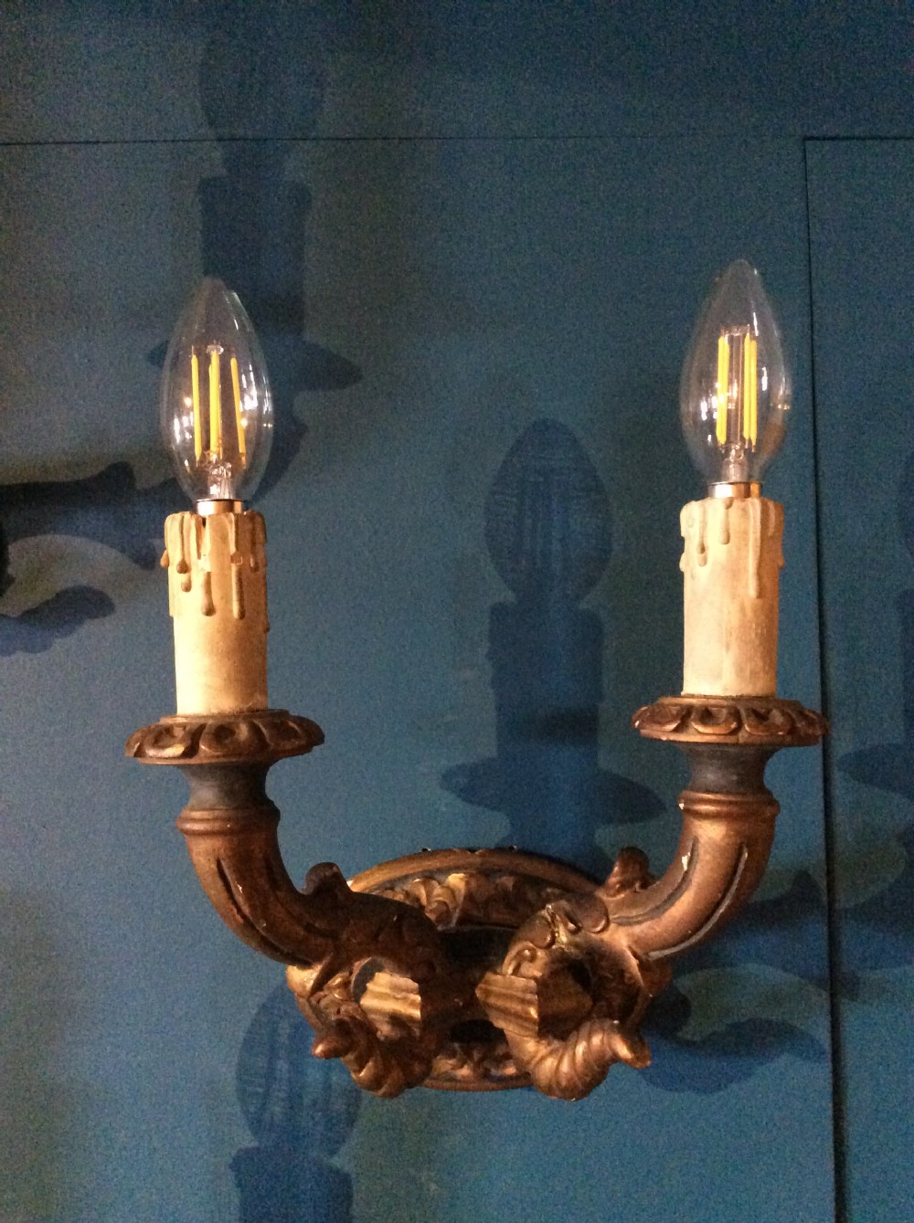 A pair of 19th-century carved and gilded twin-arm wall light brackets featuring faux candle sleeves and decorative scrollwork. View III