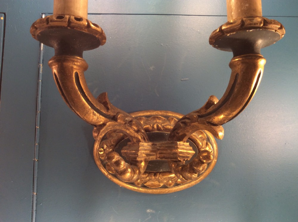 A pair of 19th-century carved and gilded twin-arm wall light brackets featuring faux candle sleeves and decorative scrollwork. View IV