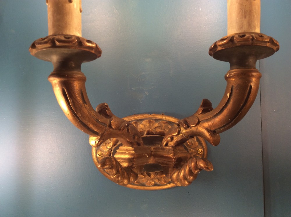 A pair of 19th-century carved and gilded twin-arm wall light brackets featuring faux candle sleeves and decorative scrollwork. View V