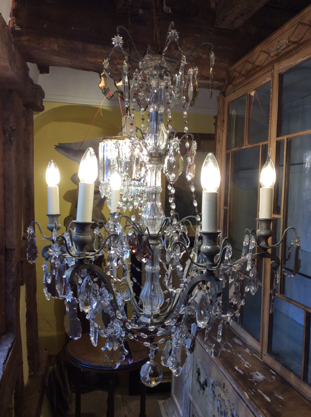 A nineteenth-century six-light chandelier featuring a central cut-glass baluster, curved metal arms, candle-style bulb holders, and cascading crystal drops.