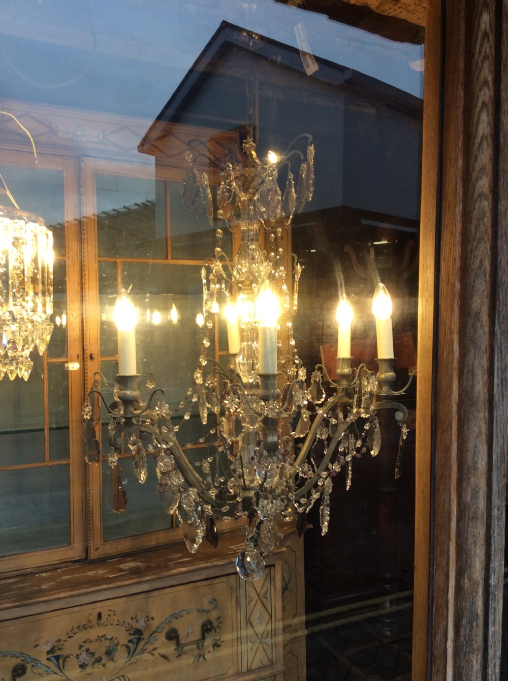 A nineteenth-century six-light chandelier featuring a central cut-glass baluster, curved metal arms, candle-style bulb holders, and cascading crystal drops. View V