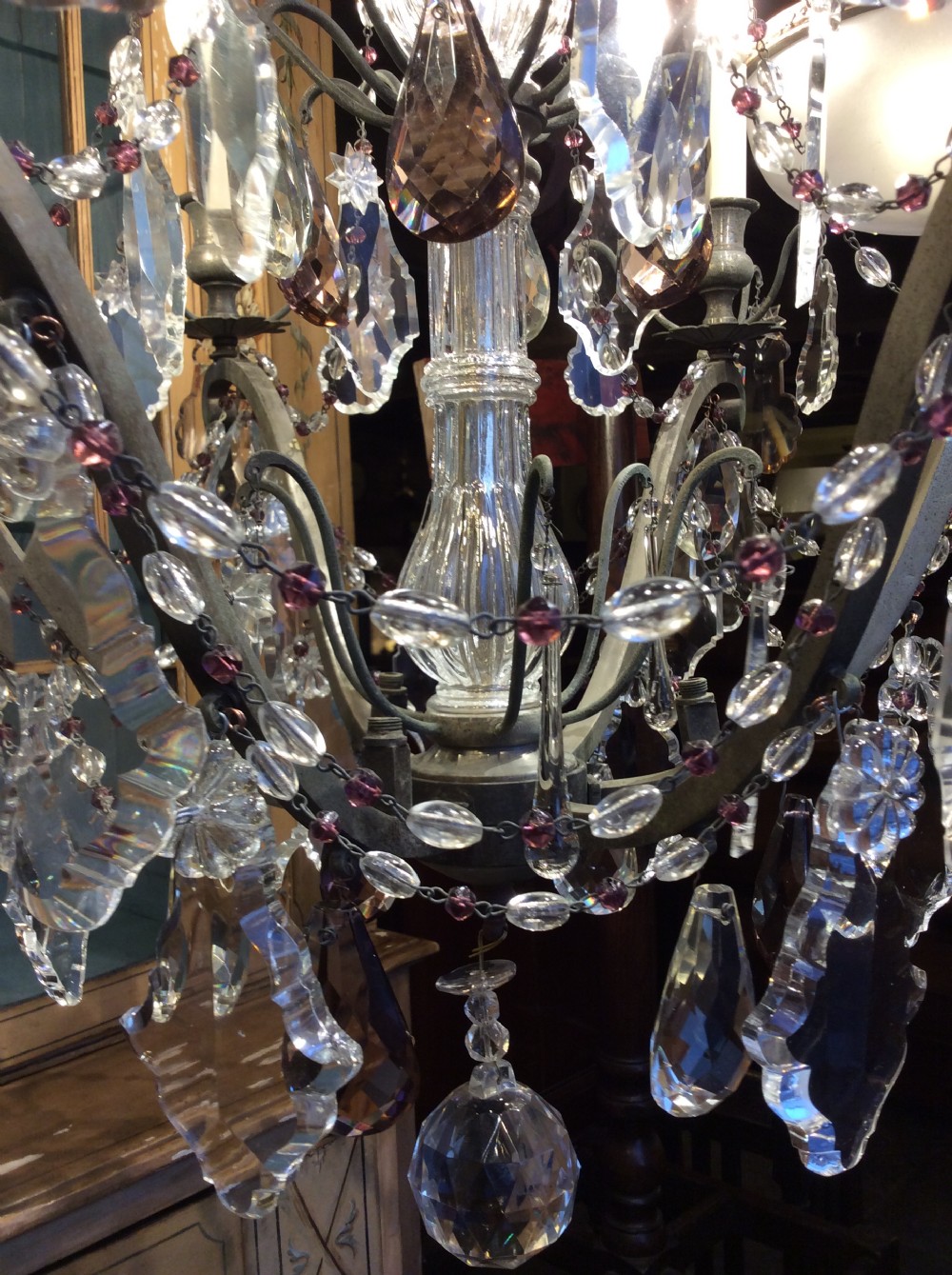 A nineteenth-century six-light chandelier featuring a central cut-glass baluster, curved metal arms, candle-style bulb holders, and cascading crystal drops. View VI