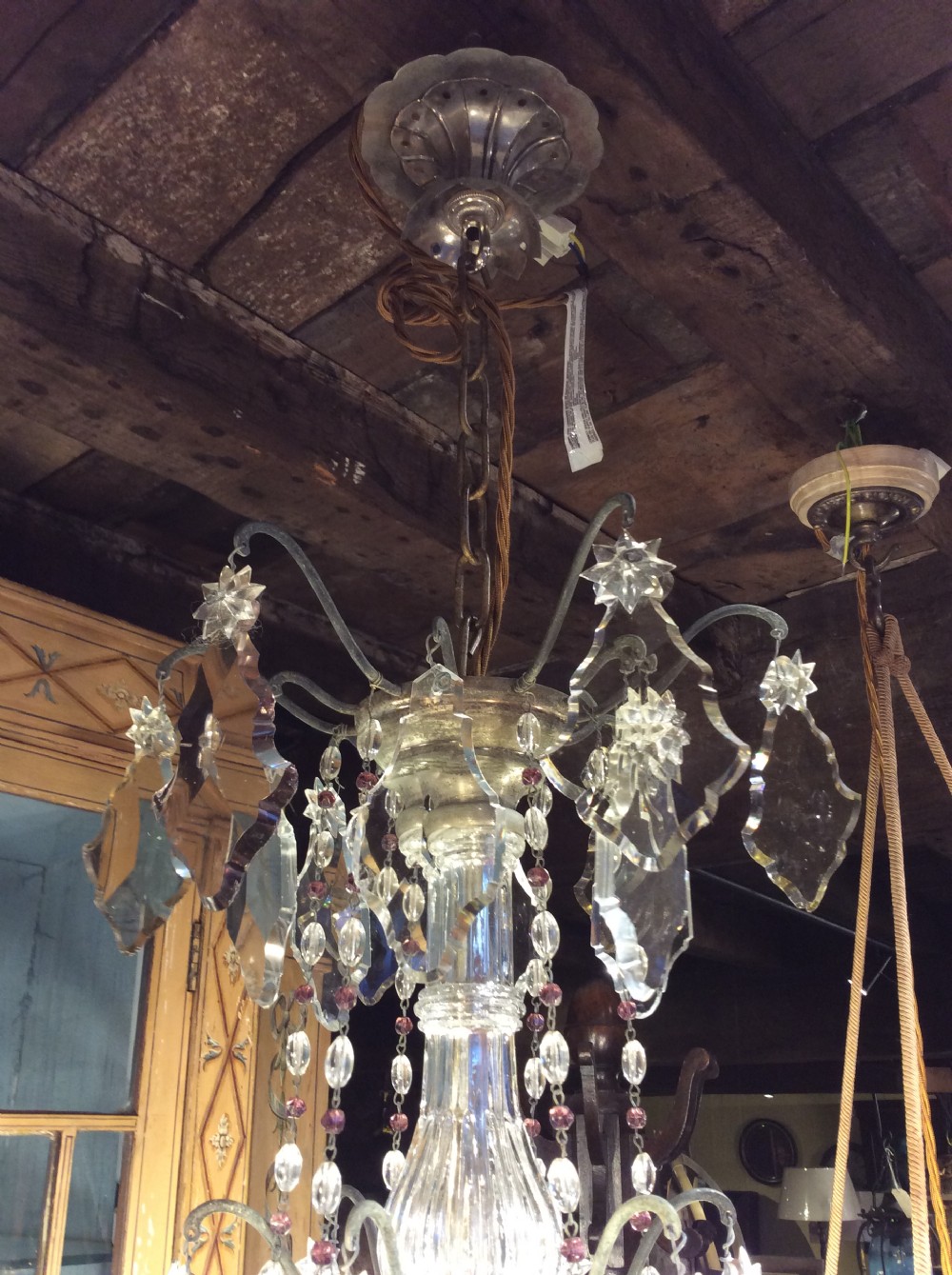 A nineteenth-century six-light chandelier featuring a central cut-glass baluster, curved metal arms, candle-style bulb holders, and cascading crystal drops. View VII