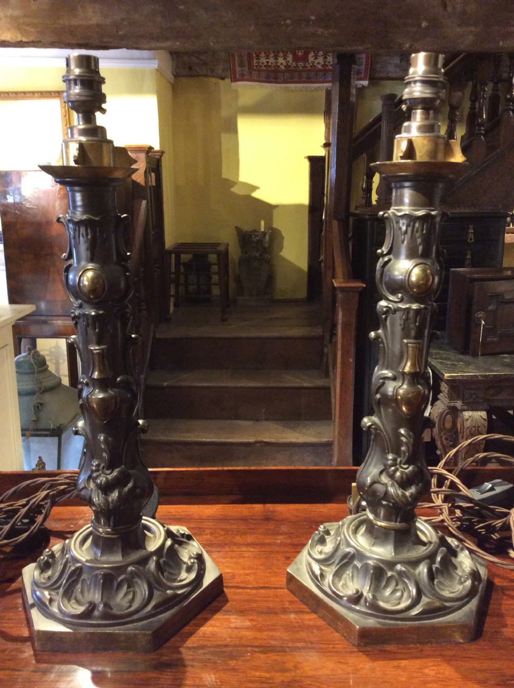 A pair of nineteenth-century repousse brass table lamps featuring ornate scrolling foliage stems on hexagonal bases.