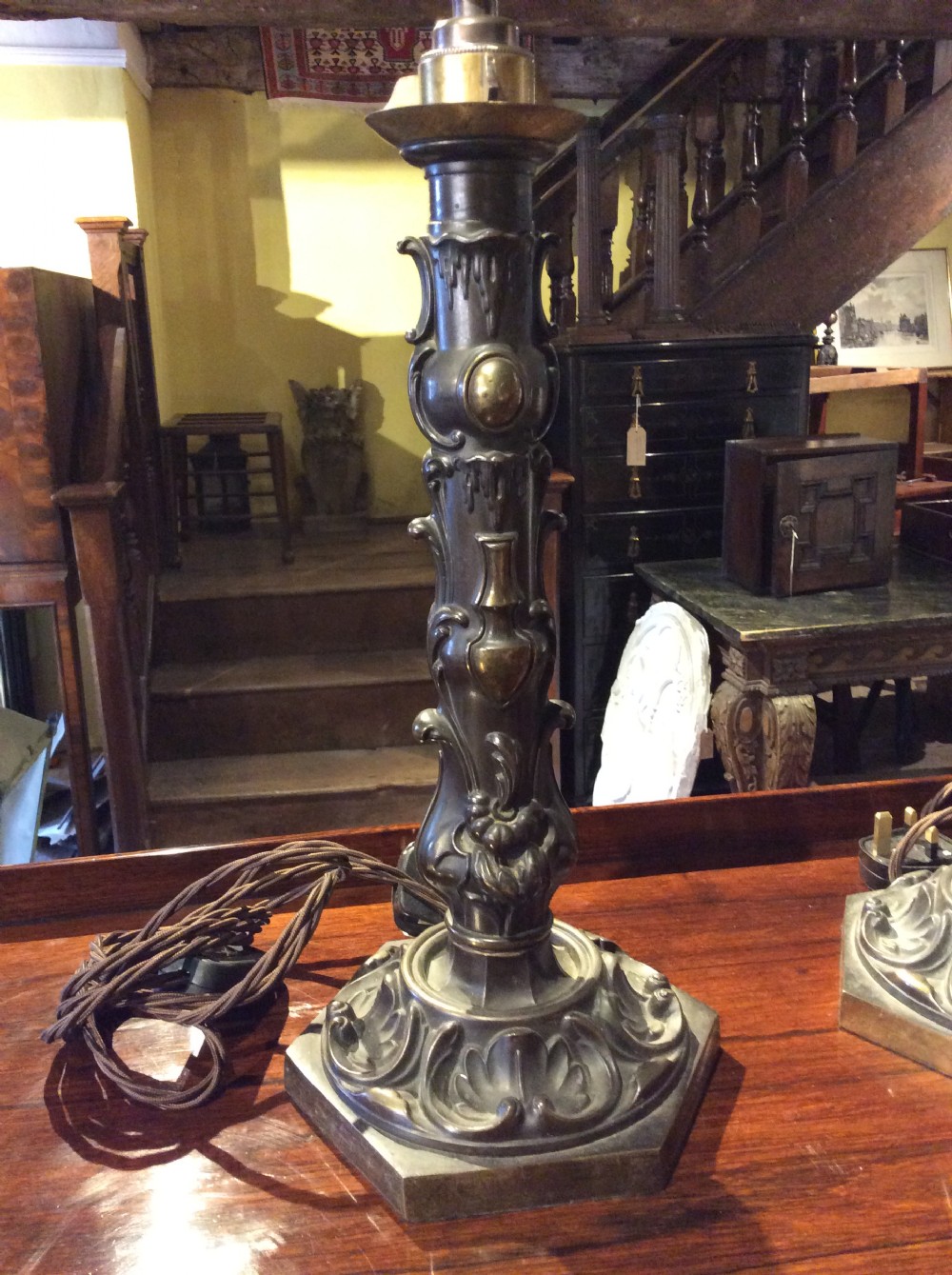 A pair of nineteenth-century repousse brass table lamps featuring ornate scrolling foliage stems on hexagonal bases. View IV