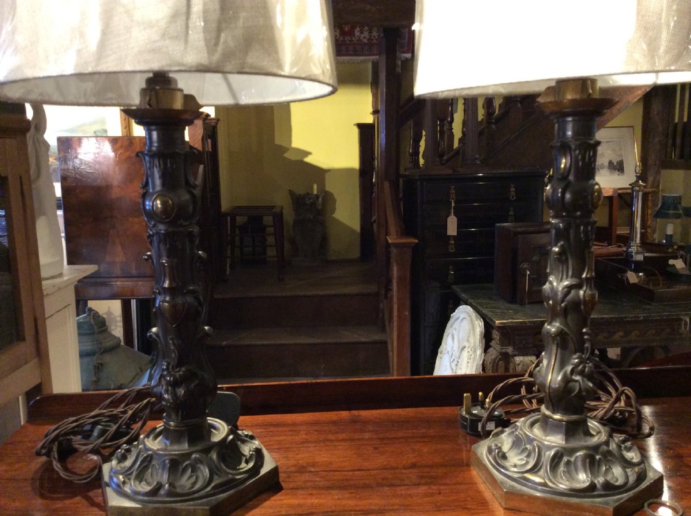 A pair of nineteenth-century repousse brass table lamps featuring ornate scrolling foliage stems on hexagonal bases. View V