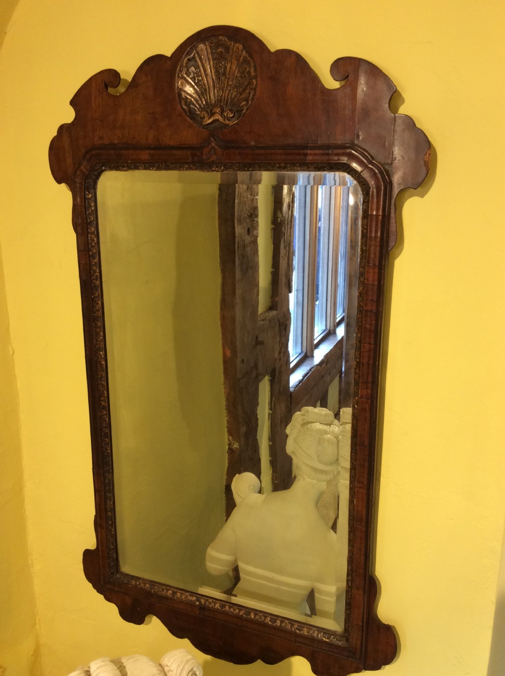 An 18th-century Queen Anne walnut wall mirror featuring a scroll-cut shaped apron and top cresting adorned with a carved gilt shell. View II