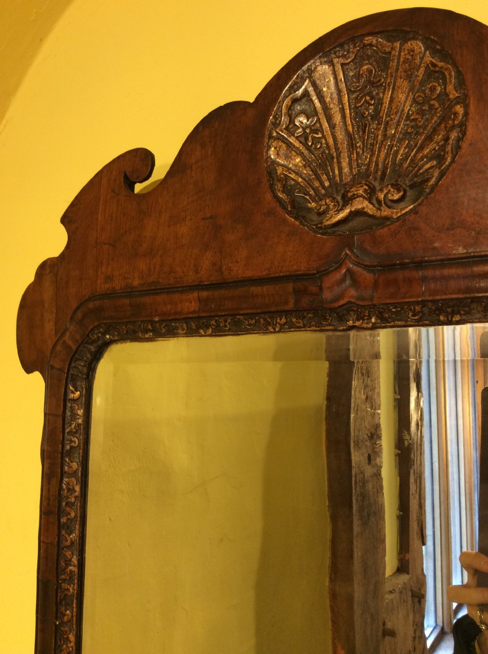 An 18th-century Queen Anne walnut wall mirror featuring a scroll-cut shaped apron and top cresting adorned with a carved gilt shell. View IV