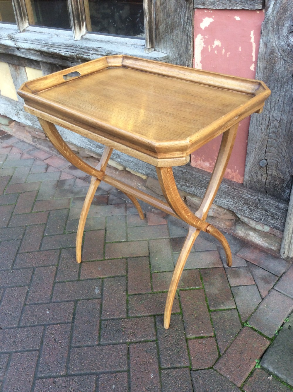 An early twentieth-century light oak butlers tray featuring cut-out handles, resting on a matching curved wooden stand. View III