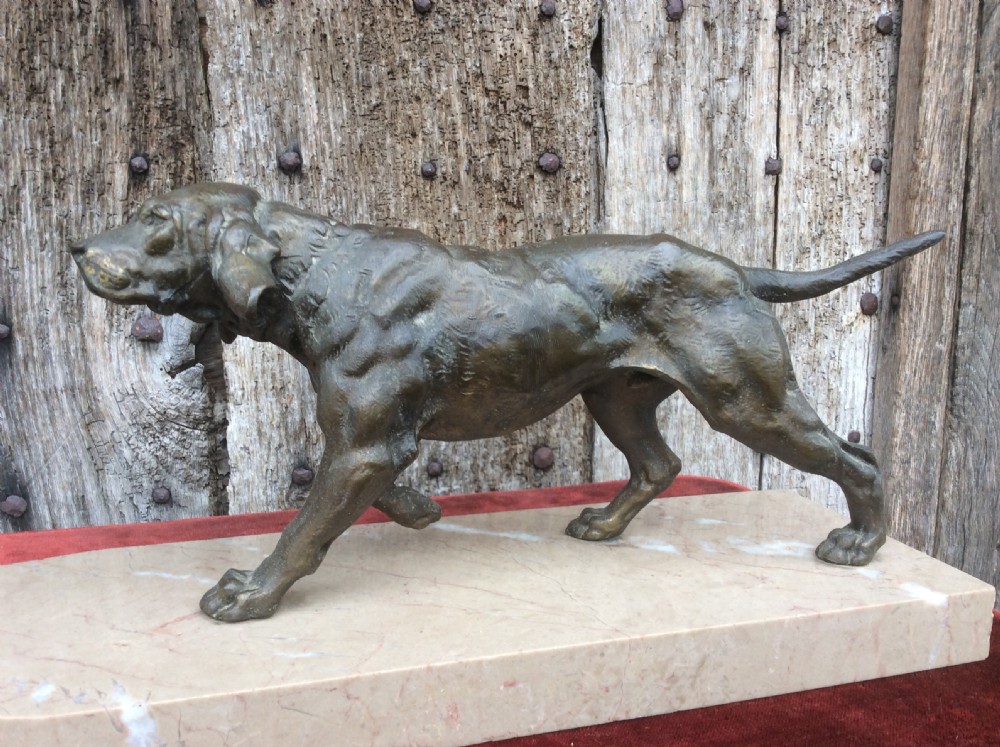 A dark bronze sculpture depicting a hunting dog stalked towards a small bird, mounted on a cream marble plinth. View IV