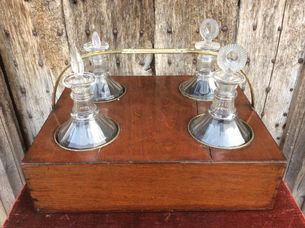An 18th-century mahogany tantalus box holding four glass decanters with circular glass stoppers and a brass overhead handle. View II
