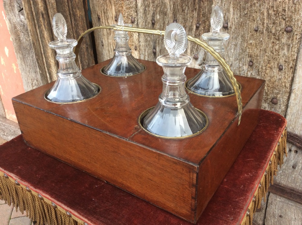 An 18th-century mahogany tantalus box holding four glass decanters with circular glass stoppers and a brass overhead handle. View III