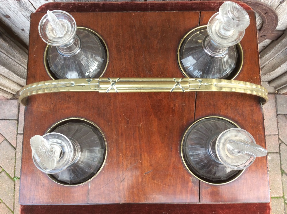 An 18th-century mahogany tantalus box holding four glass decanters with circular glass stoppers and a brass overhead handle. View V