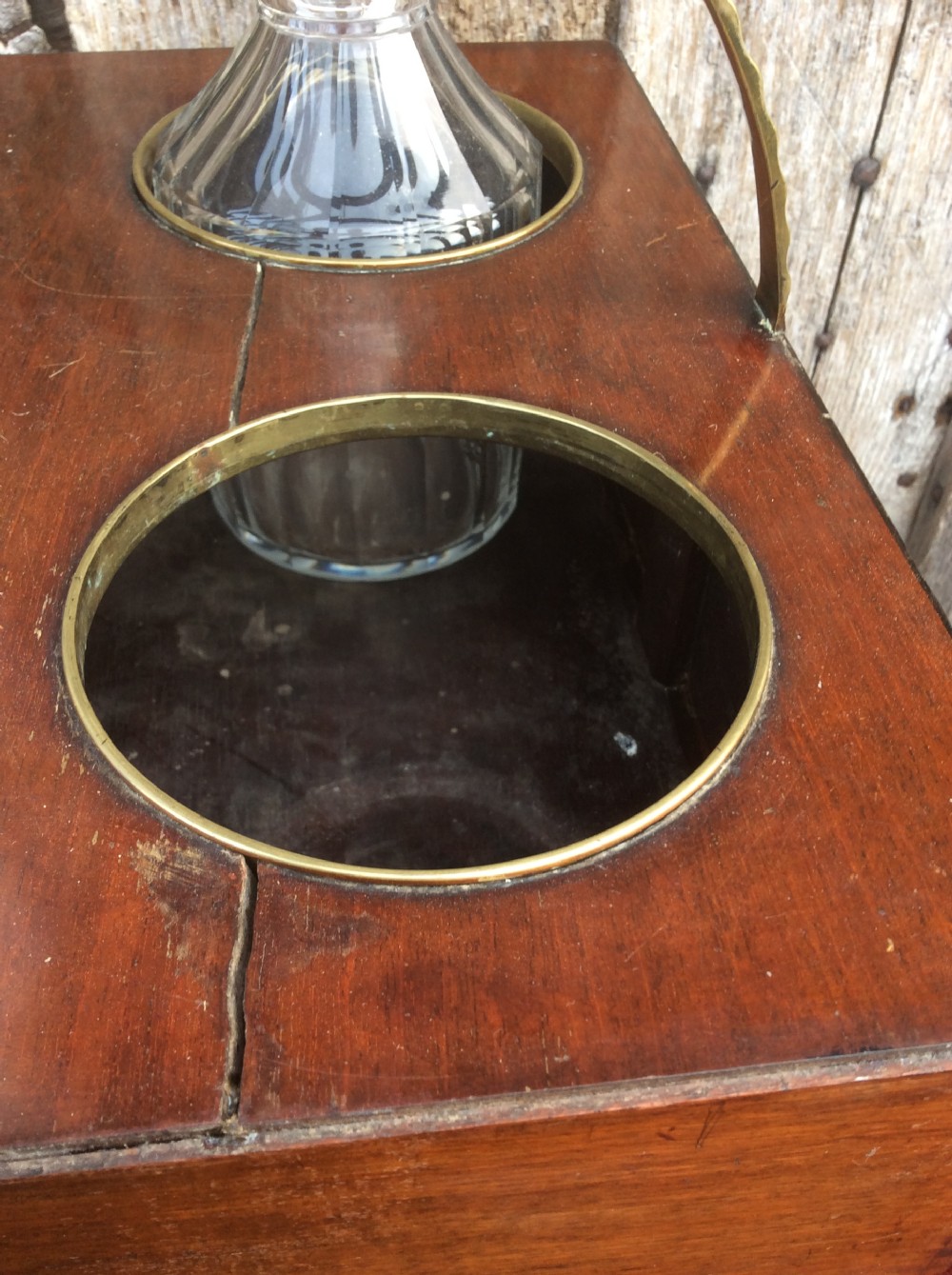 An 18th-century mahogany tantalus box holding four glass decanters with circular glass stoppers and a brass overhead handle. View VI