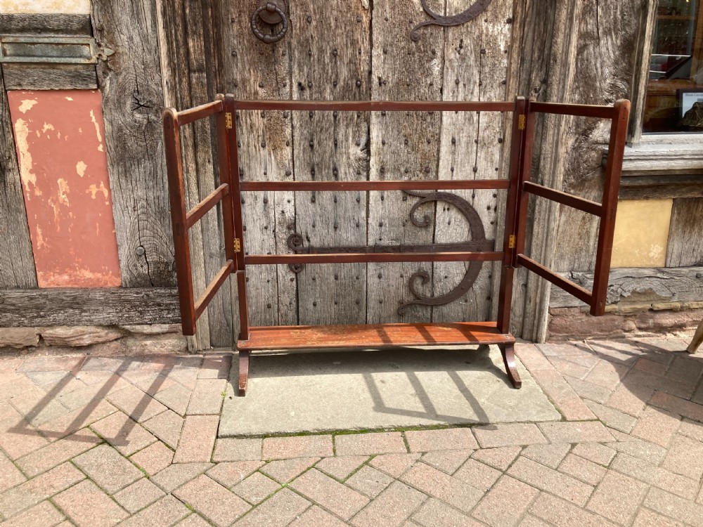 A nineteenth-century mahogany three-fold towel rail featuring horizontal drying bars, brass hinges, and a solid lower wooden shelf.