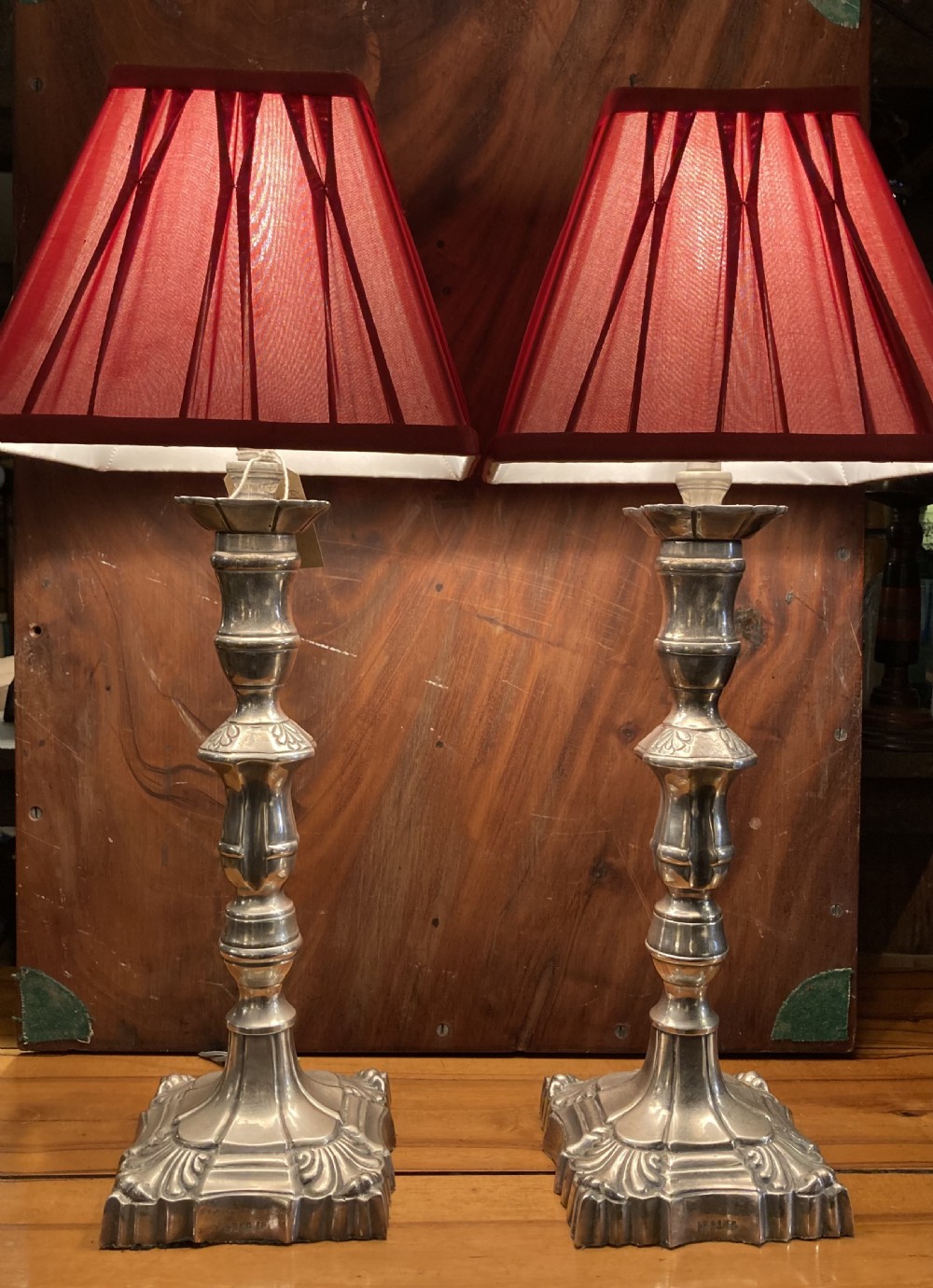 A pair of early twentieth-century silver-plated candlestick table lamps fitted with red pleated shades.