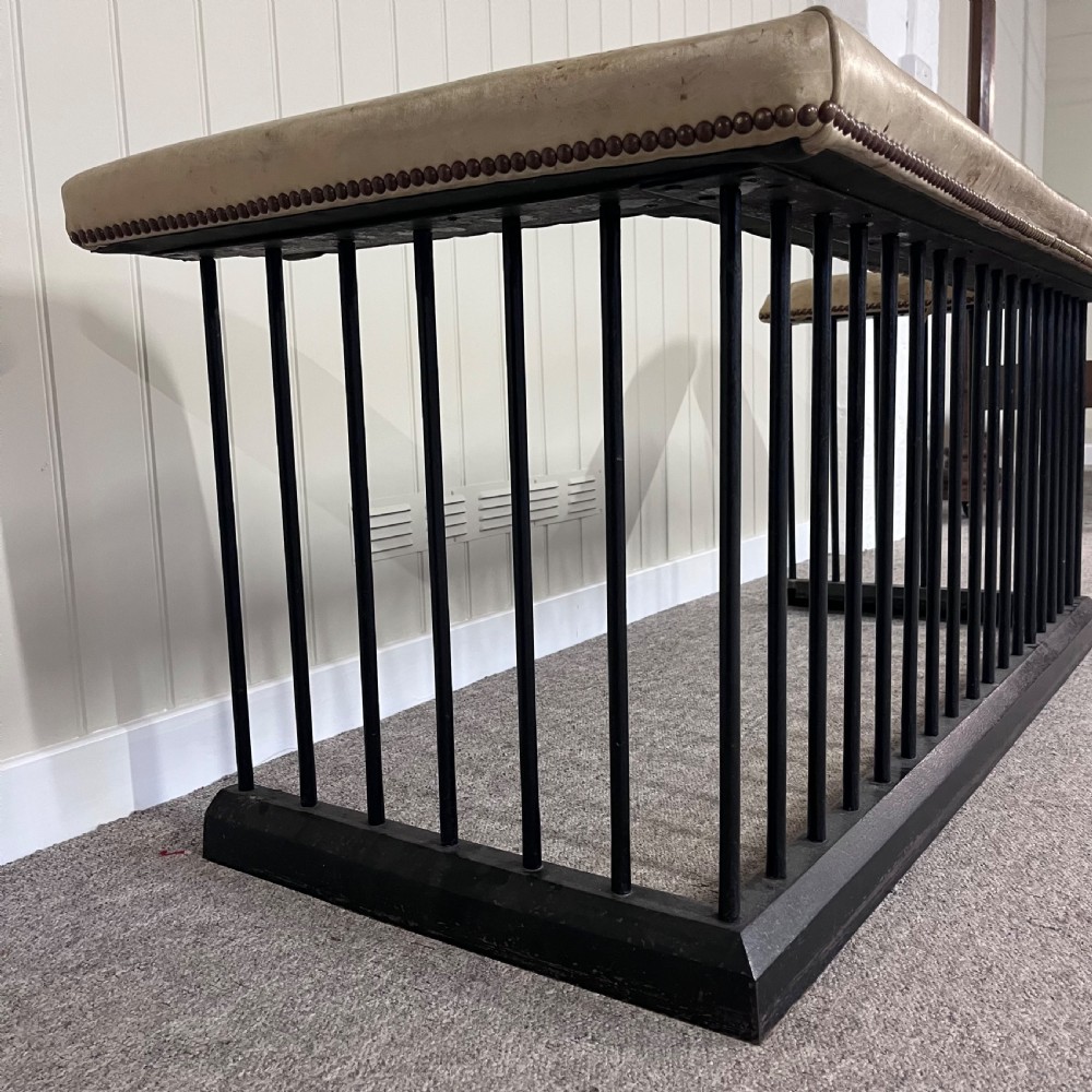 A nineteenth-century steel club fender with vertical black spindles, a solid base frame, and a tan leather upholstered rim trimmed with brass studs. View III