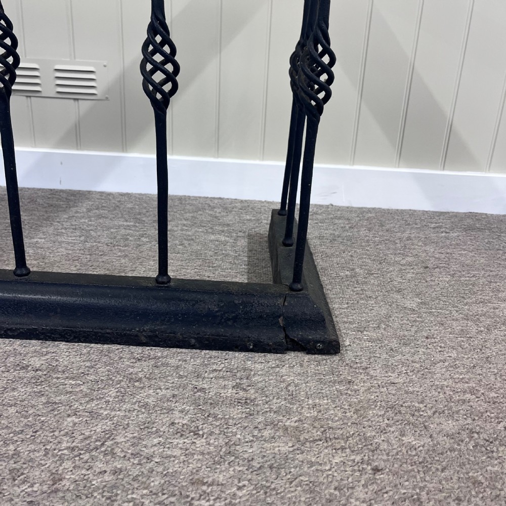 A 19th-century club fender featuring a polished mahogany top rail supported by black wrought iron twisted spindles on a low plinth base. View V