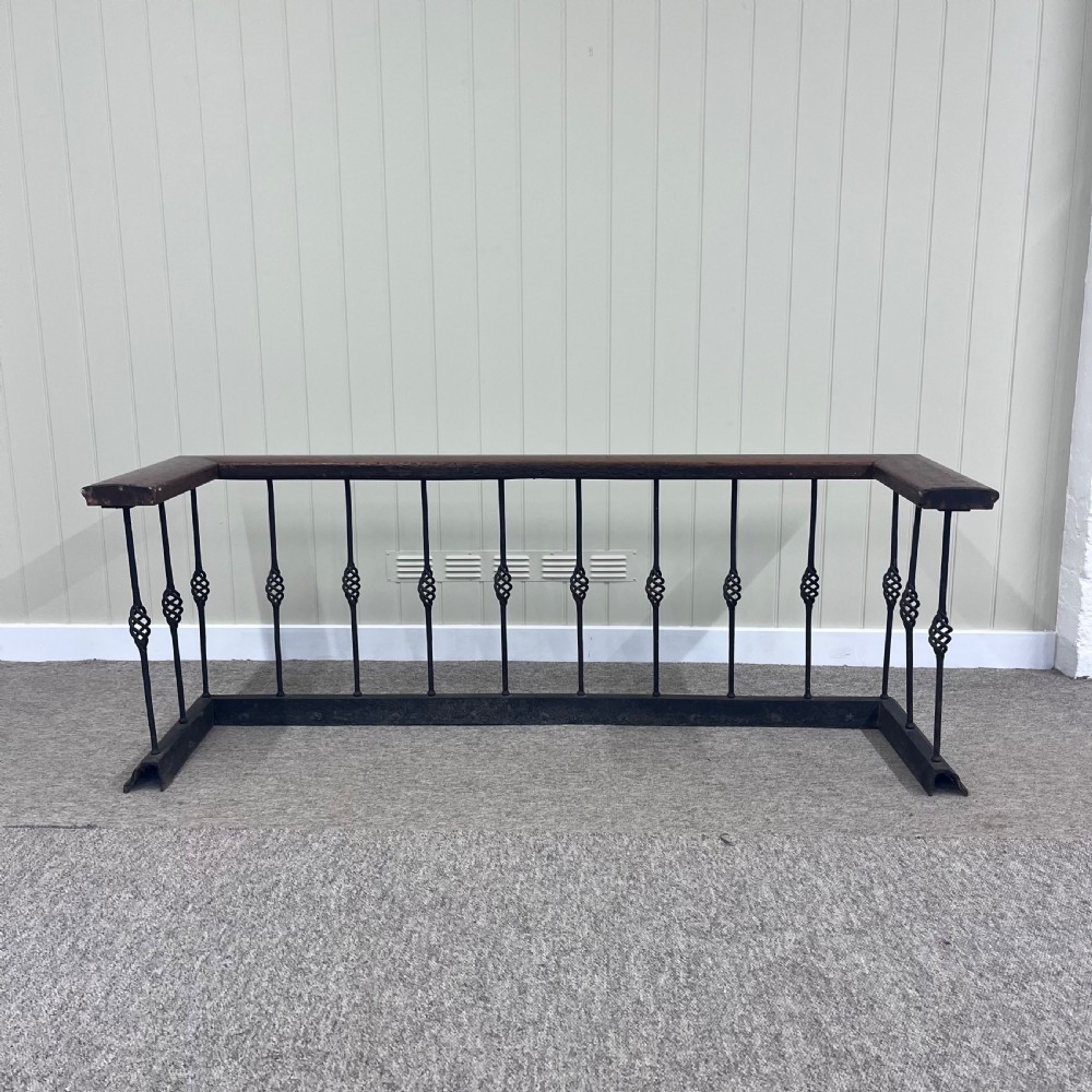 A 19th-century club fender featuring a polished mahogany top rail supported by black wrought iron twisted spindles on a low plinth base. View VI