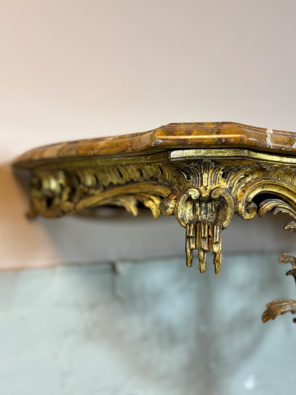 A pair of 18th-century carved giltwood side tables with openwork scrolling pedestal bases and marble tops. View X