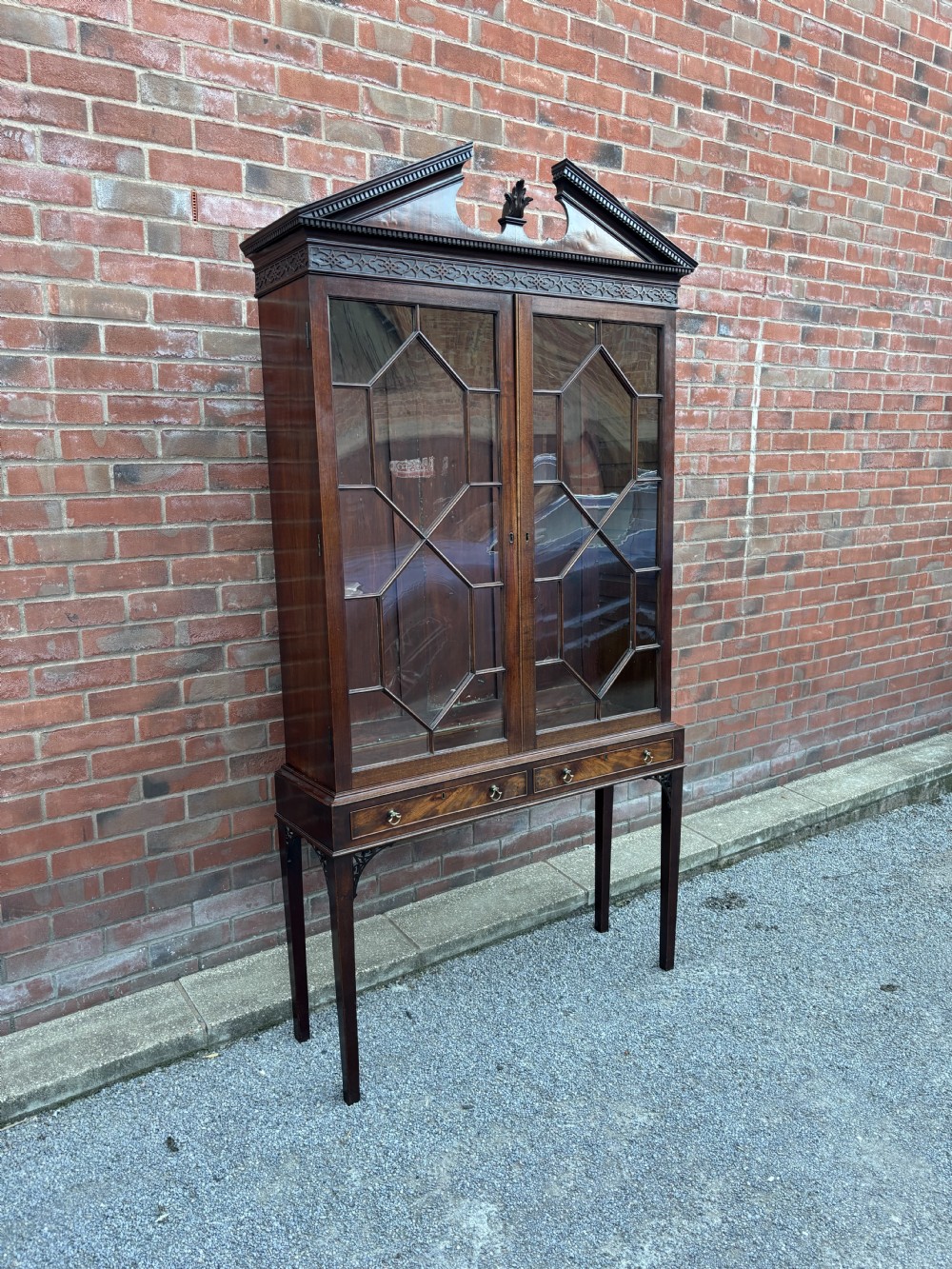An 18th-century Chippendale mahogany display cabinet on stand featuring a broken pediment, astragal glazed doors, two drawers, and square legs. View IV
