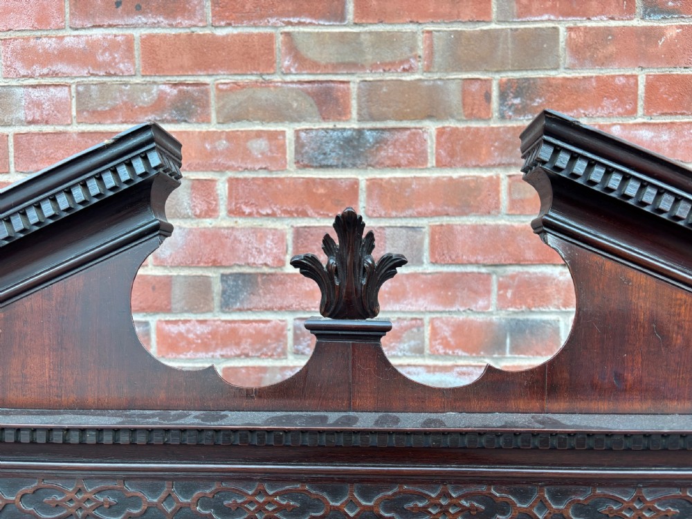 An 18th-century Chippendale mahogany display cabinet on stand featuring a broken pediment, astragal glazed doors, two drawers, and square legs. View VI