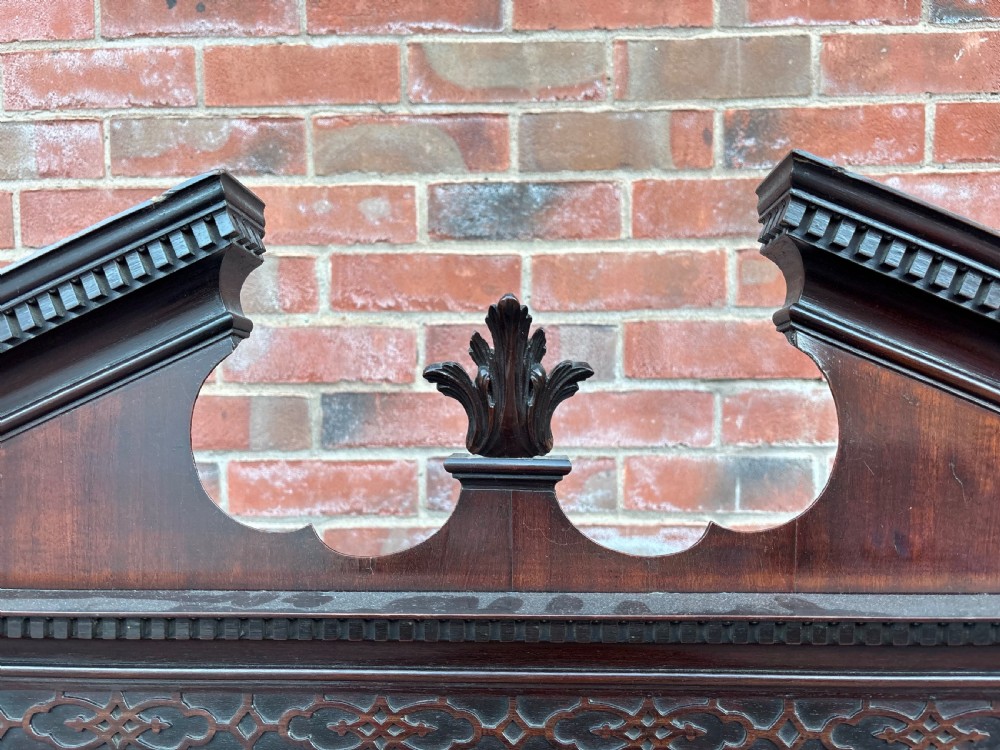 An 18th-century Chippendale mahogany display cabinet on stand featuring a broken pediment, astragal glazed doors, two drawers, and square legs. View VIII