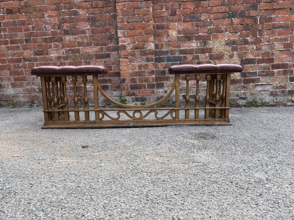A 19th-century cast steel club fender with turned balusters, decorative lower scrollwork, and two corner seats upholstered in deep-buttoned burgundy leather with metal stud trim. View II