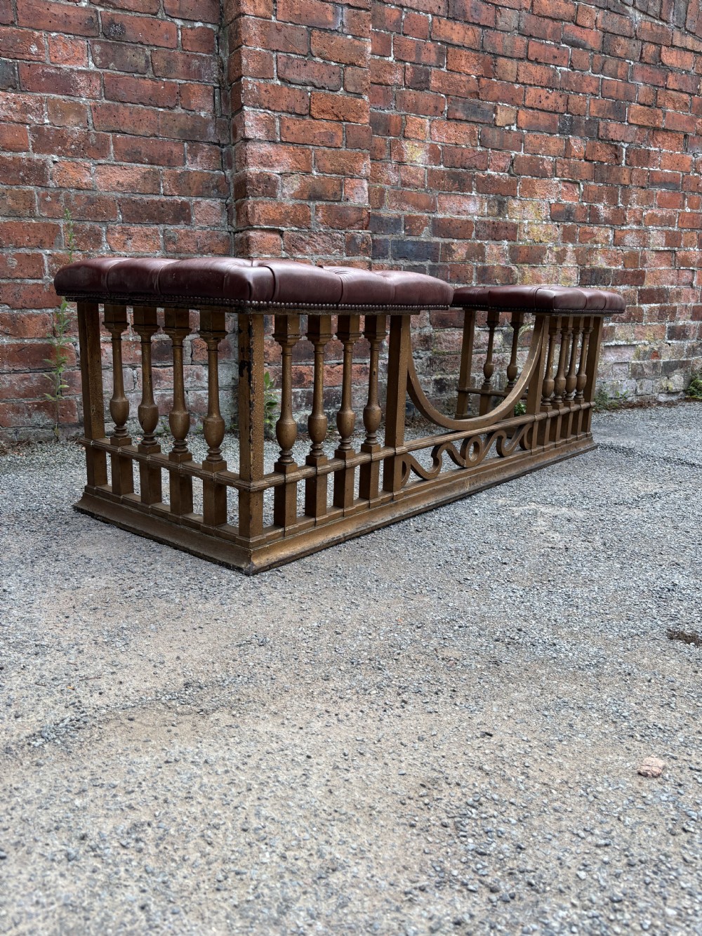 A 19th-century cast steel club fender with turned balusters, decorative lower scrollwork, and two corner seats upholstered in deep-buttoned burgundy leather with metal stud trim. View III
