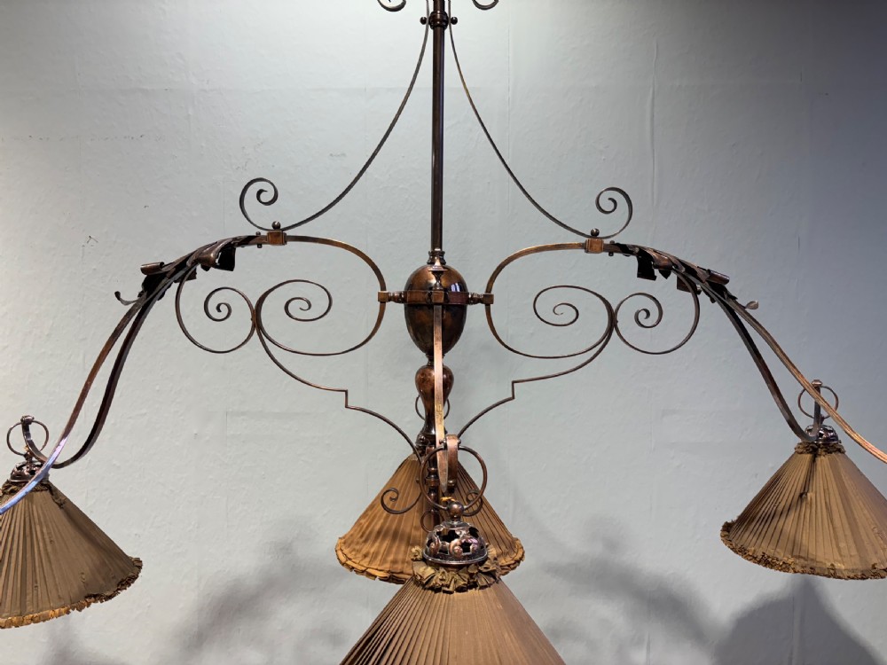 A 19th-century wrought iron six-arm billiard light fixture with decorative scrollwork and pleated conical fabric shades with fringed borders. View III